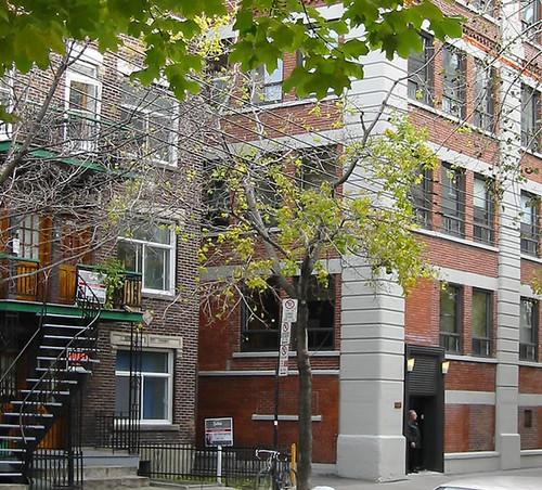 Brick front with an outdoor staircase and a tree.